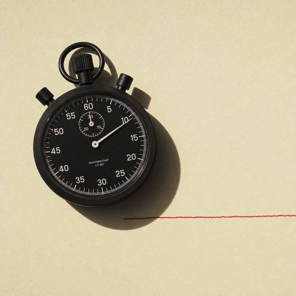 Black stopwatch beside a red pen line on cream paper